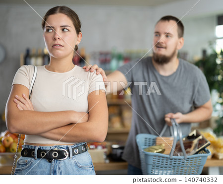 Young man calming irritated woman in grocery store Young man calming irritated woman in grocery store 140740332