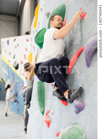 Young man practicing rock climbing on climbing wall Young man practicing rock climbing on climbing wall 140740441