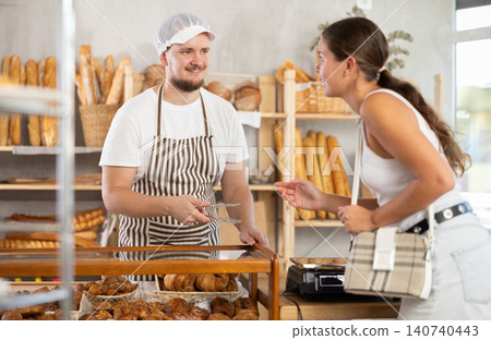 Salesman gives croissants to young girl in bakery 140740443