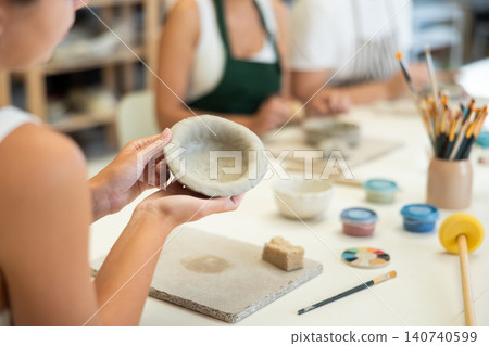 Closeup of female hands molding clay into plate in pottery workshop Closeup of female hands molding clay into plate in pottery workshop 140740599