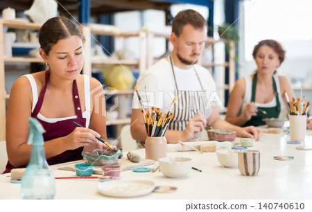 Pottery workers paint ceramic plates together at table Pottery workers paint ceramic plates together at table 140740610