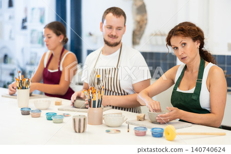 Three students in pottery workshop learn to create homemade plates and other utensils Three students in pottery workshop learn to create homemade plates and other utensils 140740624