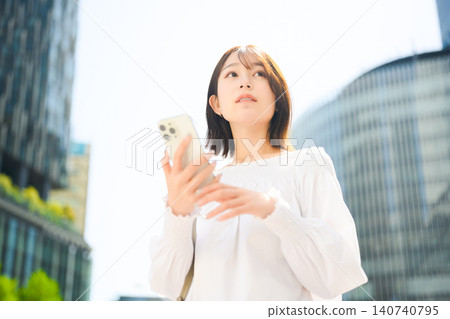 A woman holding a smartphone, streetscape A woman holding a smartphone, streetscape 140740795
