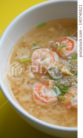 rice soup with shrimp in white bowl on yellow background rice soup with shrimp in white bowl on yellow background 140740821