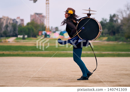 Beautiful Latina woman with a hat dancing with a drum and cymbals on her back, overflowing with joy. Chinchinera, a street musician who dances and plays her drum in the streets. Chilean heritage, Beautiful Latina woman with a hat dancing with a drum and cymbals on her back, overflowing with joy. Chinchinera, a street musician who dances and plays her drum in the streets. Chilean heritage, 140741309