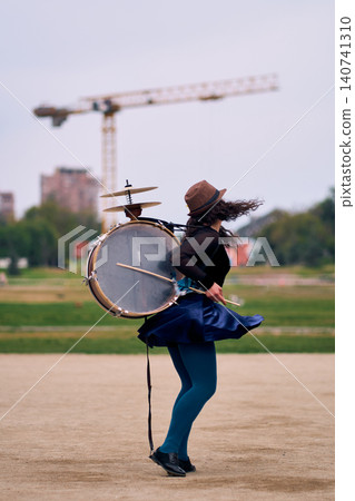 Beautiful Latina woman with a hat dancing with a drum and cymbals on her back, overflowing with joy. Chinchinera, a street musician who dances and plays her drum in the streets. Chilean heritage, Beautiful Latina woman with a hat dancing with a drum and cymbals on her back, overflowing with joy. Chinchinera, a street musician who dances and plays her drum in the streets. Chilean heritage, 140741310
