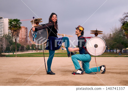 A couple of urban musicians, posing happily and romantically, she placing her foot on the man's knee, chinchineros, street musicians who play the bass drum and dance in the streets, Chilean cultural A couple of urban musicians, posing happily and romantically, she placing her foot on the man's knee, chinchineros, street musicians who play the bass drum and dance in the streets, Chilean cultural 140741337