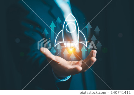 Businessman hand presenting virtual rocket ship icon with rising arrows for startup launch and business growth concept. Businessman hand presenting virtual rocket ship icon with rising arrows for startup launch and business growth concept. 140741411