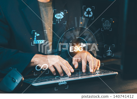 Businessman typing on laptop keyboard with virtual ESG icon representing Environmental, Social and Governance criteria. 140741412