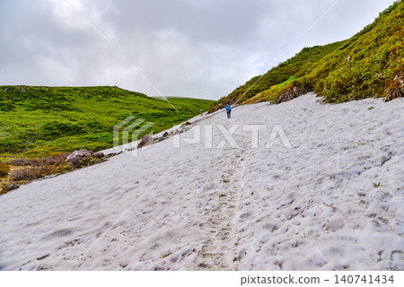 晴朗的夏日：在鳥海山西之河原附近廣闊的雪原上，可以看到登山者的背影，以及周圍的山景。 140741434