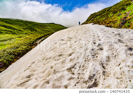 晴朗的夏日:在鳥海山西之河原附近廣闊的雪原上,可以看到登山者的背影,以及周圍的山景。 晴朗的夏日:在鳥海山西之河原附近廣闊的雪原上,可以看到登山者的背影,以及周圍的山景。 140741435