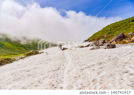 晴朗的夏日:在鳥海山西之河原附近廣闊的雪原上,可以看到登山者的背影,以及周圍的山景。 晴朗的夏日:在鳥海山西之河原附近廣闊的雪原上,可以看到登山者的背影,以及周圍的山景。 140741437