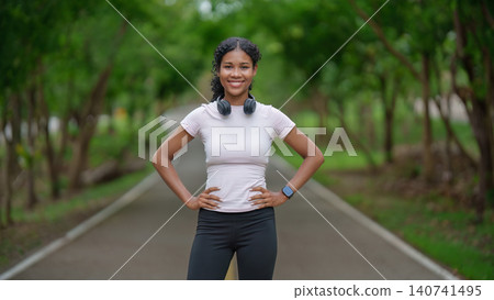 Confident Black woman with headphones on park path for fitness Confident Black woman with headphones on park path for fitness 140741495