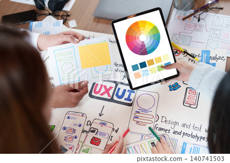 Group collaborating on UI UX design with sketches and tablet color palette Group collaborating on UI UX design with sketches and tablet color palette 140741503