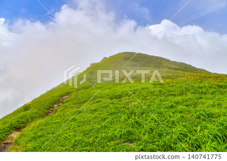 晴朗的夏日:白雲在鳥海山的健行步道和綠色山坡上緩緩升起。 晴朗的夏日:白雲在鳥海山的健行步道和綠色山坡上緩緩升起。 140741775