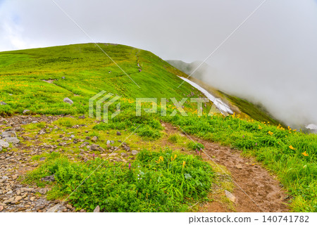晴朗的夏日:白雲在鳥海山的健行步道和綠色山坡上緩緩升起。 晴朗的夏日:白雲在鳥海山的健行步道和綠色山坡上緩緩升起。 140741782