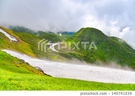 在晴朗的夏日,鳥海山籠罩在上升的雲霧之中,露出了白雪皚皚的山坡和漫山遍野的雪景。 在晴朗的夏日,鳥海山籠罩在上升的雲霧之中,露出了白雪皚皚的山坡和漫山遍野的雪景。 140741839