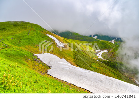 On a clear summer day, Mount Chokai is shrouded in rising clouds, revealing its snow-capped slopes and a landscape of snow flowing across the mountainside. On a clear summer day, Mount Chokai is shrouded in rising clouds, revealing its snow-capped slopes and a landscape of snow flowing across the mountainside. 140741841