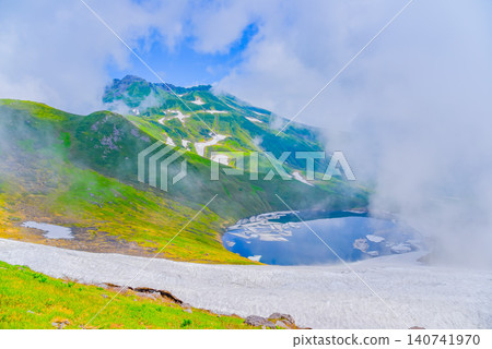 On a clear summer day, a glimpse of the summit of Mount Chokai and the beautifully expansive Lake Chokai below, seen through a break in the clouds. 140741970