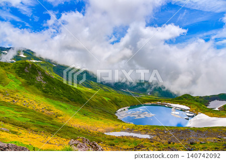 On a clear summer day, snowdrifts adorn the mystical crater lake, Lake Chokai, on Mount Chokai, creating a beautiful reflection of the summer sky. On a clear summer day, snowdrifts adorn the mystical crater lake, Lake Chokai, on Mount Chokai, creating a beautiful reflection of the summer sky. 140742092