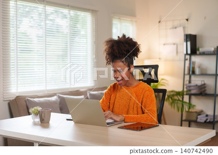 Young African American woman smiling while engaged in virtual meeting at home. Young African American woman smiling while engaged in virtual meeting at home. 140742490