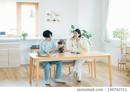 與狗狗共度的家庭生活:一對夫婦在客廳和心愛的狗狗一起玩耍。 與狗狗共度的家庭生活:一對夫婦在客廳和心愛的狗狗一起玩耍。 140742551