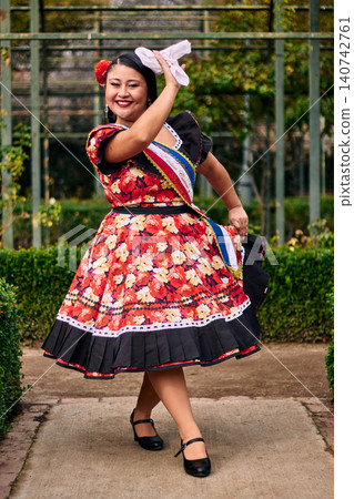 Portrait of a beautiful, smiling young woman, happily dressed in a Chilean huasa, celebrating, playing with her handkerchief, and posing to dance cueca, a traditional Chilean dance. Chilean traditions Portrait of a beautiful, smiling young woman, happily dressed in a Chilean huasa, celebrating, playing with her handkerchief, and posing to dance cueca, a traditional Chilean dance. Chilean traditions 140742761