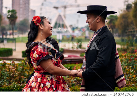 Portrait of a smiling young couple, dressed as Chilean huasos, posing romantically, about to kiss and dance cueca, a traditional Chilean dance. Chilean traditions, celebration, and culture. Portrait of a smiling young couple, dressed as Chilean huasos, posing romantically, about to kiss and dance cueca, a traditional Chilean dance. Chilean traditions, celebration, and culture. 140742766