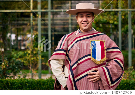 Portrait of a smiling, cheerful young man dressed as a Chilean huaso, celebrating and posing to dance cueca, a traditional Chilean dance. Chilean traditions, celebration, and culture. Portrait of a smiling, cheerful young man dressed as a Chilean huaso, celebrating and posing to dance cueca, a traditional Chilean dance. Chilean traditions, celebration, and culture. 140742769