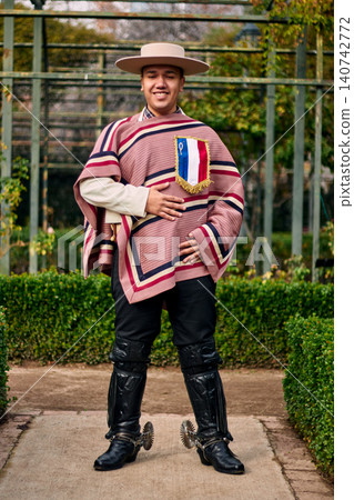 Portrait of a smiling, cheerful young man dressed as a Chilean huaso, celebrating and posing to dance cueca, a traditional Chilean dance. Chilean traditions, celebration, and culture. Portrait of a smiling, cheerful young man dressed as a Chilean huaso, celebrating and posing to dance cueca, a traditional Chilean dance. Chilean traditions, celebration, and culture. 140742772