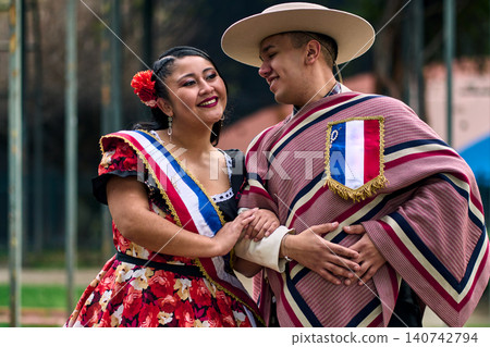 Portrait of a smiling young couple, dressed as Chilean huasos, looking at each other and posing romantically to dance cueca, a traditional Chilean dance. Chilean traditions, celebrations, and culture. Portrait of a smiling young couple, dressed as Chilean huasos, looking at each other and posing romantically to dance cueca, a traditional Chilean dance. Chilean traditions, celebrations, and culture. 140742794