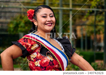 Portrait of a beautiful young woman smiling, cheerfully dressed as a Chilean huasa, joyfully celebrating and posing to dance the cueca, a traditional Chilean dance. Chilean traditions. Portrait of a beautiful young woman smiling, cheerfully dressed as a Chilean huasa, joyfully celebrating and posing to dance the cueca, a traditional Chilean dance. Chilean traditions. 140742828