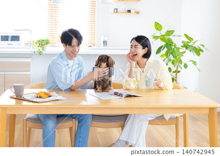 與狗狗共度的家庭生活:一對夫婦在客廳和心愛的狗狗一起玩耍。 與狗狗共度的家庭生活:一對夫婦在客廳和心愛的狗狗一起玩耍。 140742945