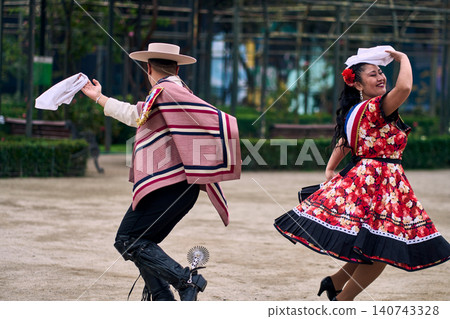 Portrait of a smiling young couple dressed as Chilean huasos, joyfully dancing Portrait of a smiling young couple dressed as Chilean huasos, joyfully dancing 140743328