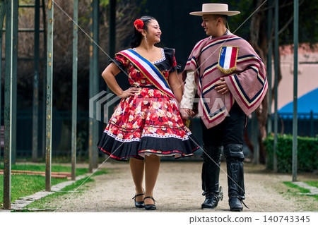 Portrait of a smiling young couple, dressed as Chilean huasos, looking at each other 140743345