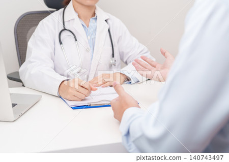 Doctor and patient having a medical consultation in a hospital room, explaining a treatment plan, discussing diagnosis, and giving advice during a medical health checkup appointment in a clinic 140743497