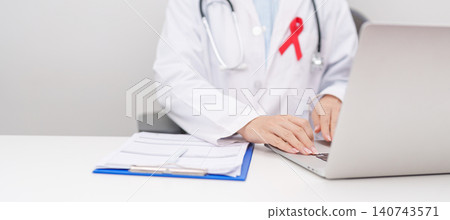 doctor using laptop and report notes on notebook. red ribbon concept of December World Aids Day, MADD, October Red ribbon week, February Heart month, Marfan Syndrome, May Stroke awareness 140743571