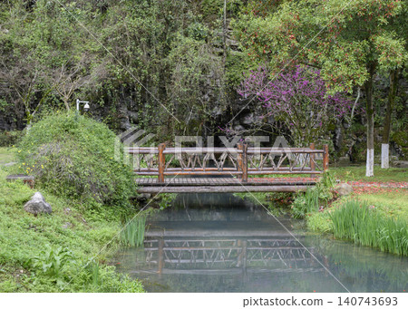 Small wooden bridge over a pond in the Yellow Dragon Park in the mountains near Zhangjiajie, China 140743693