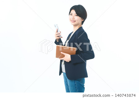 畫面中,一台相機在白色背景前,手持智慧型手機和棕色資料夾。 畫面中,一台相機在白色背景前,手持智慧型手機和棕色資料夾。 140743874