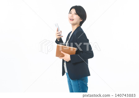 她手裡拿著一部智慧型手機和一個棕色文件夾,直視鏡頭。 她手裡拿著一部智慧型手機和一個棕色文件夾,直視鏡頭。 140743883