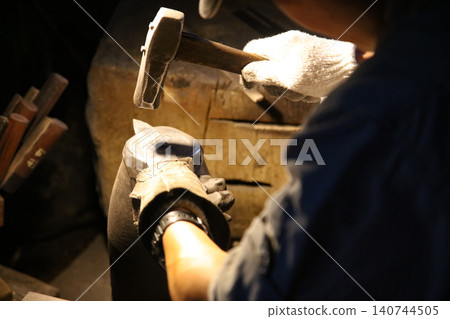 A craftsman carefully straightening a knife 140744505