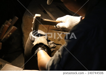 A craftsman carefully straightening a knife 140744506