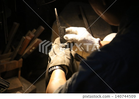 A craftsman carefully straightening a knife A craftsman carefully straightening a knife 140744509