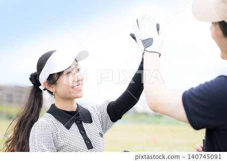 A scene depicting a man and woman enjoying golf high-fiving each other in celebration, expressing the sense of success and accomplishment in sports. A scene depicting a man and woman enjoying golf high-fiving each other in celebration, expressing the sense of success and accomplishment in sports. 140745091