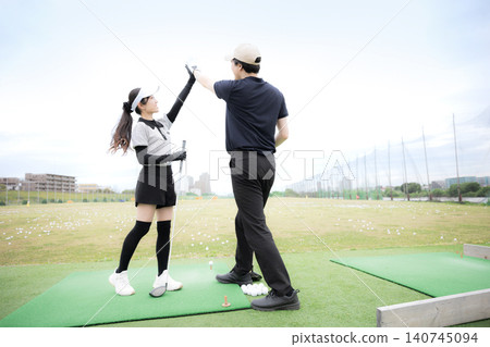 A scene depicting a man and woman enjoying golf high-fiving each other in celebration, expressing the sense of success and accomplishment in sports. A scene depicting a man and woman enjoying golf high-fiving each other in celebration, expressing the sense of success and accomplishment in sports. 140745094