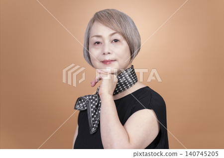 Studio portrait photography of a senior woman, with a beige background. Studio portrait photography of a senior woman, with a beige background. 140745205