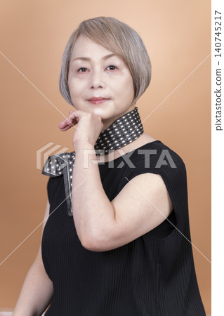 Studio portrait photography of a senior woman, with a beige background. Studio portrait photography of a senior woman, with a beige background. 140745217