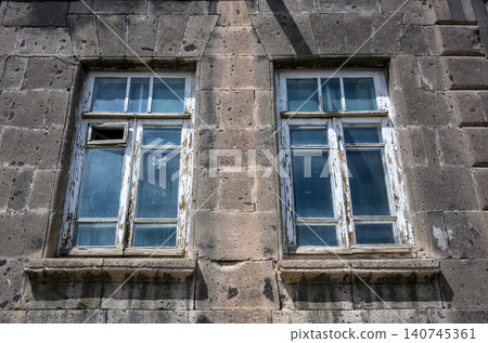 Close-up of aged stone building with two faded window frames Close-up of aged stone building with two faded window frames 140745361
