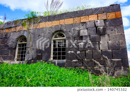Weathered stone wall with arched openings and wild greenery Weathered stone wall with arched openings and wild greenery 140745382