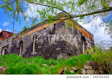 Historic stone structure with arched openings, surrounded by greenery 140745383